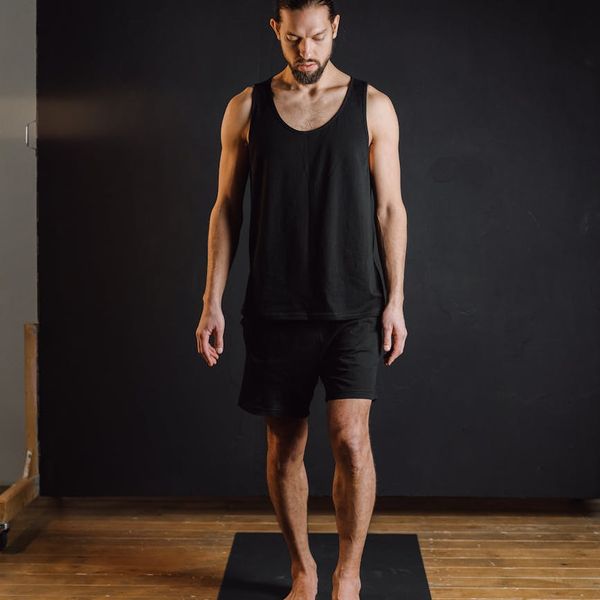 Smiling woman sitting in a lotus yoga pose in a sunlit studio.